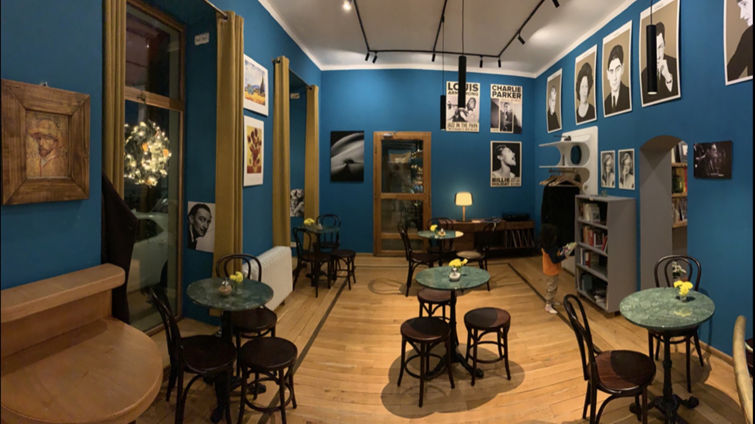 Kirschblüte Bonn Altstadt Kneipe Café Camus Innenraum mit türkisblauen Wänden, kleinen Marmortischen, Holzstühlen und Porträts an den Wänden im gemütlichen Altbauambiente